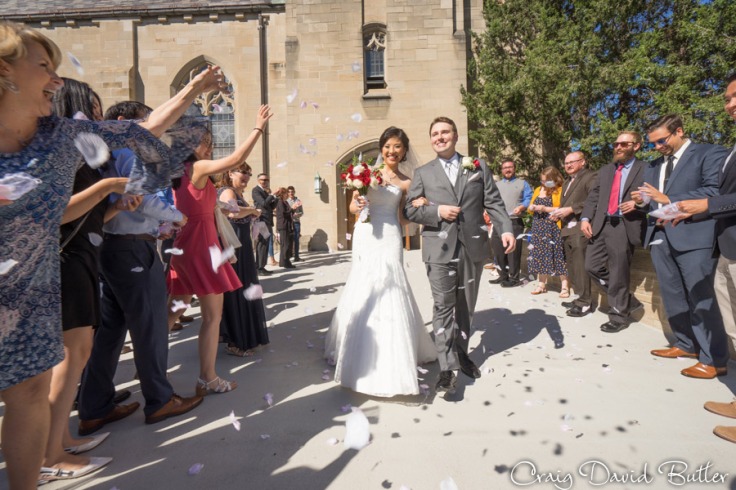 Bride and groom exit the church with rose petals